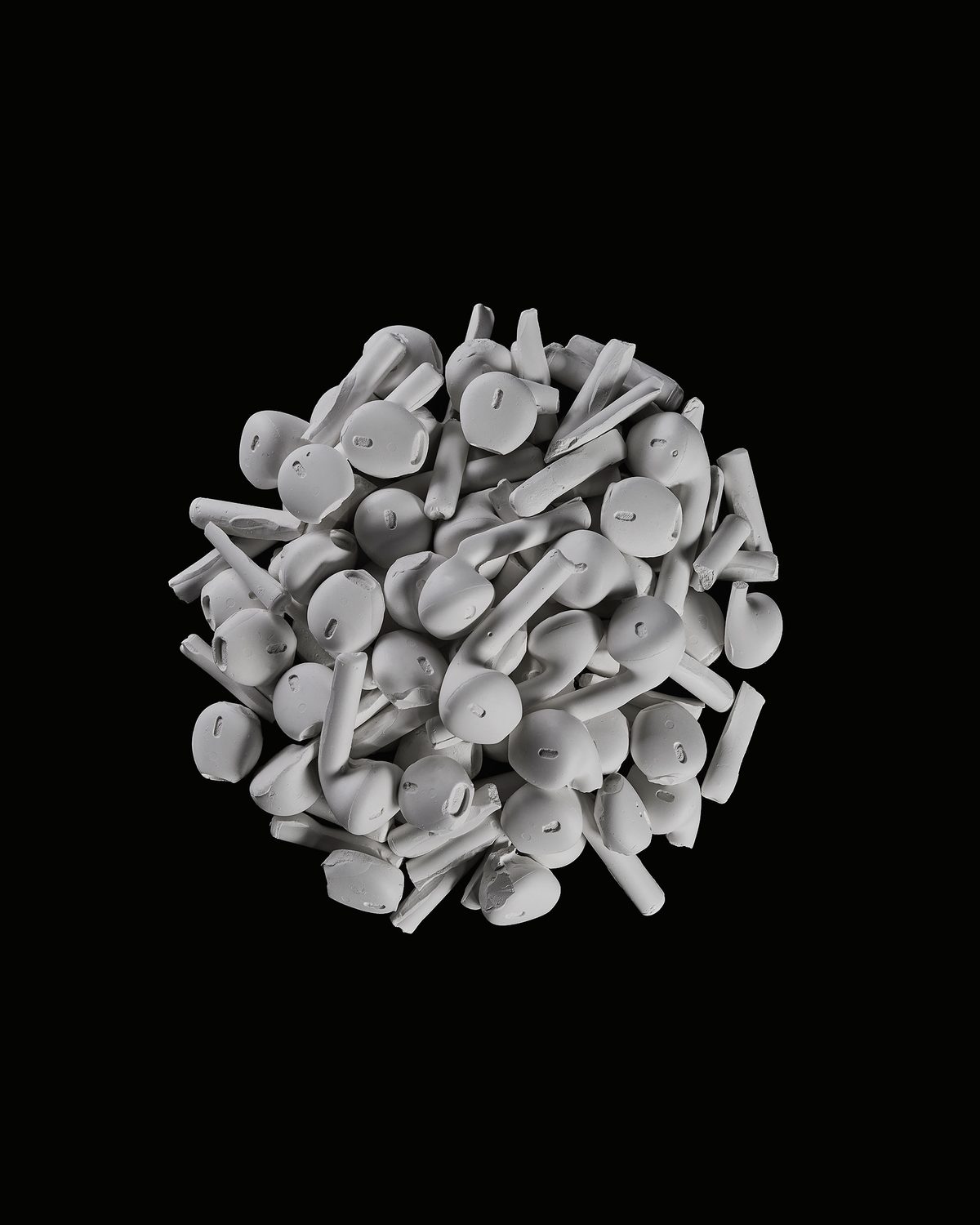 A round cluster of white plaster casts of earphones on black