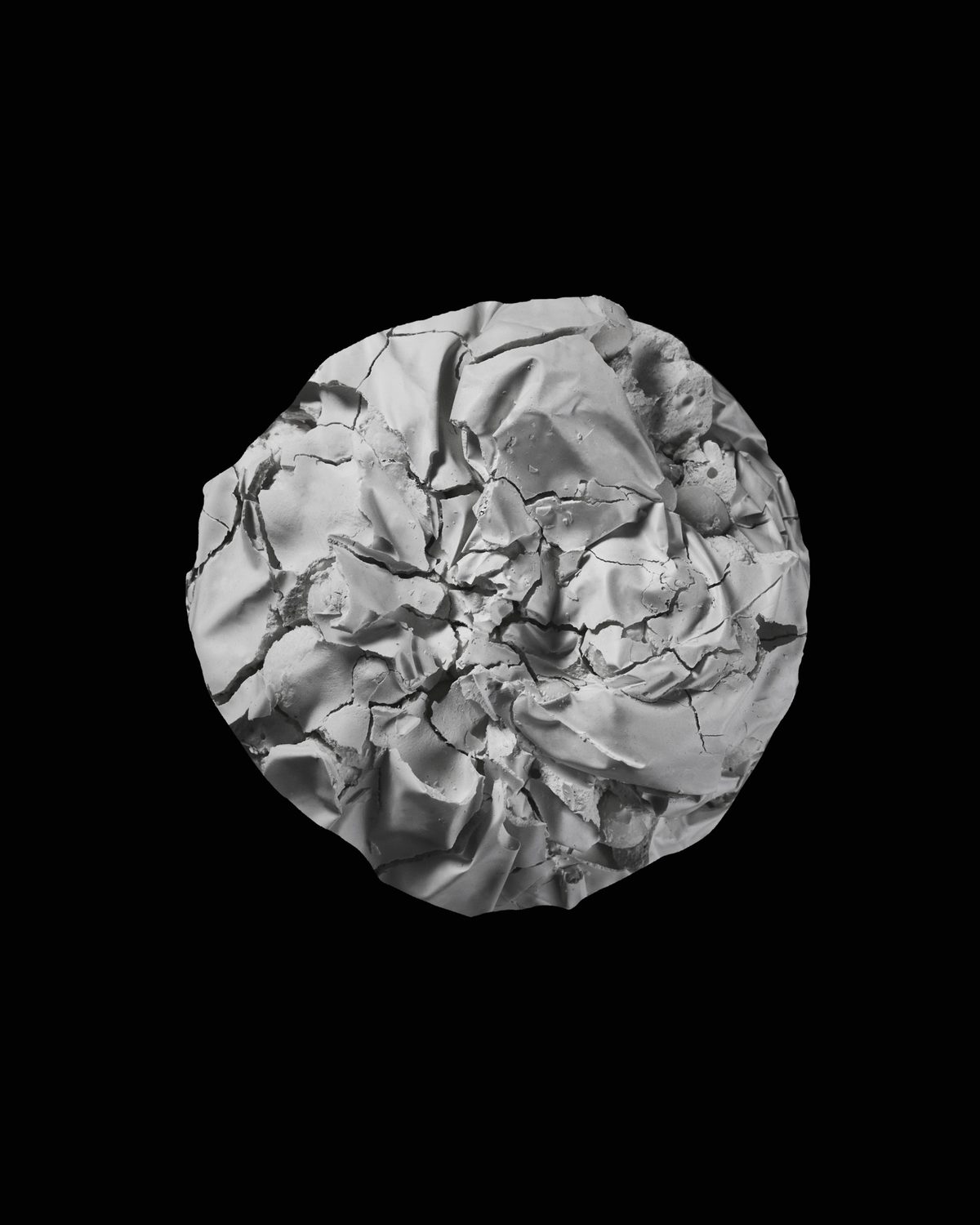 A round, crumpled and cracked white plaster form on black