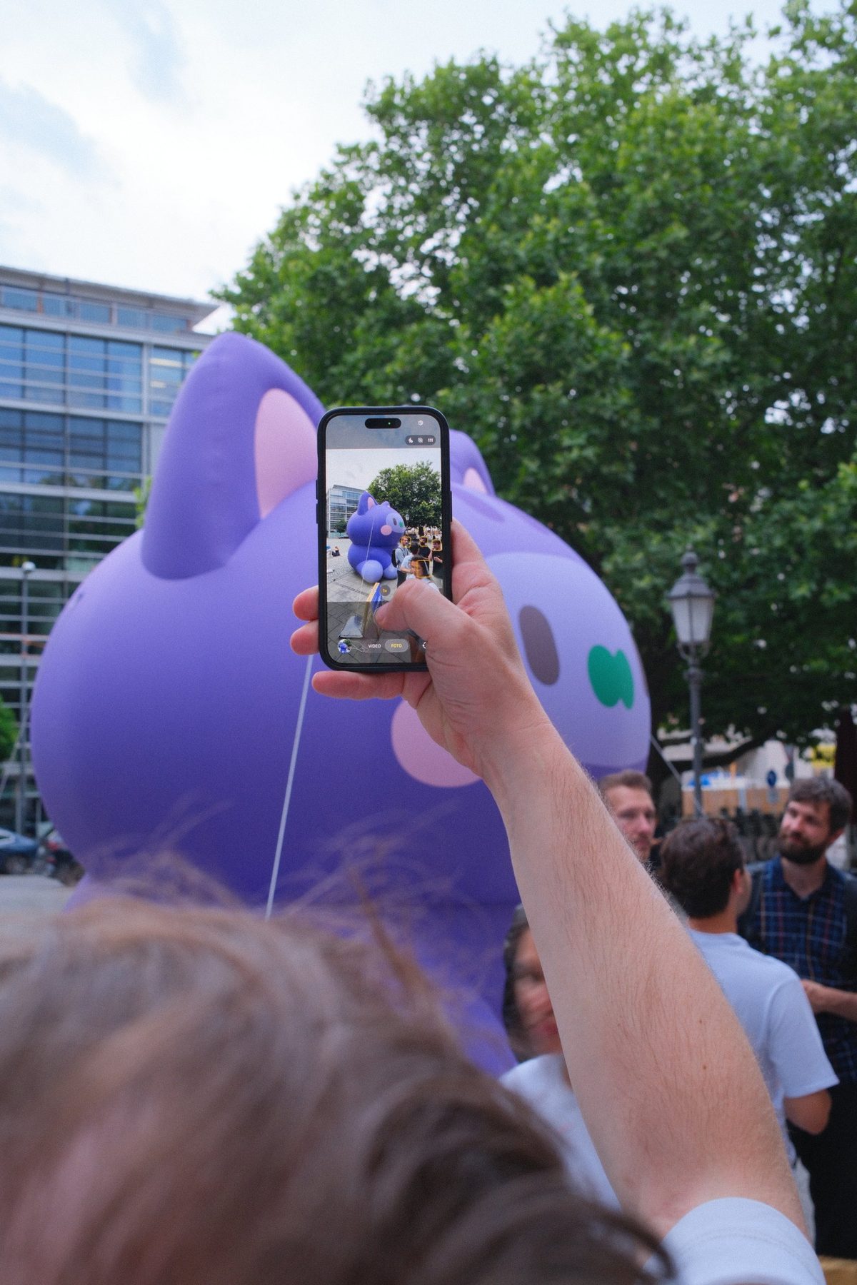 A visitor photographing the inflatable cat with a smartphone on the Rindermarkt