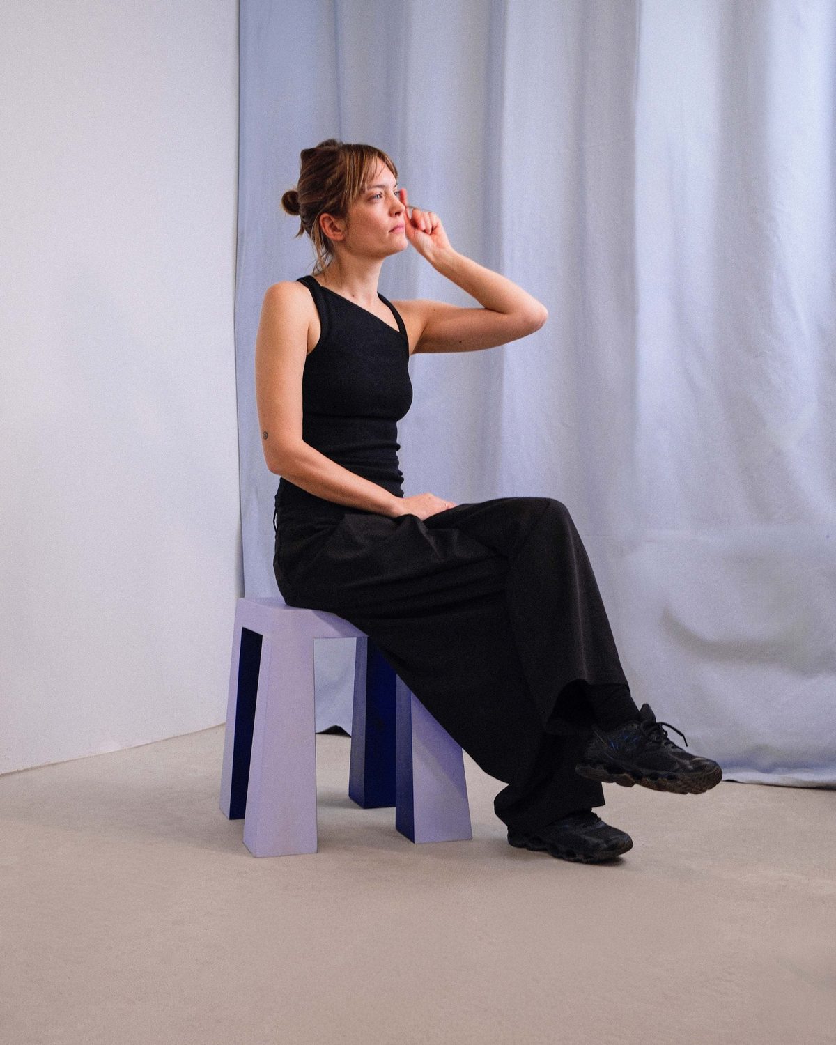 Pia sitting on the lilac Flare-Stool, its legs widening toward the floor