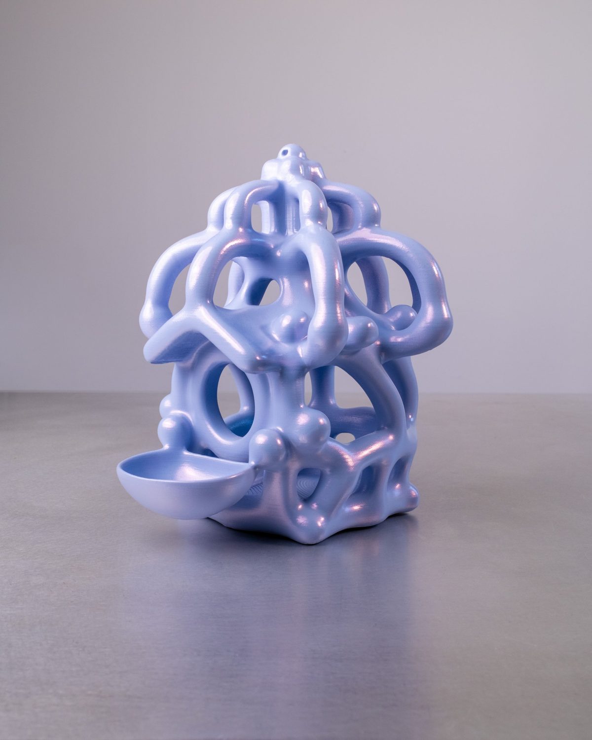 Pale blue sculptural birdhouse with looping forms and a small feeding bowl