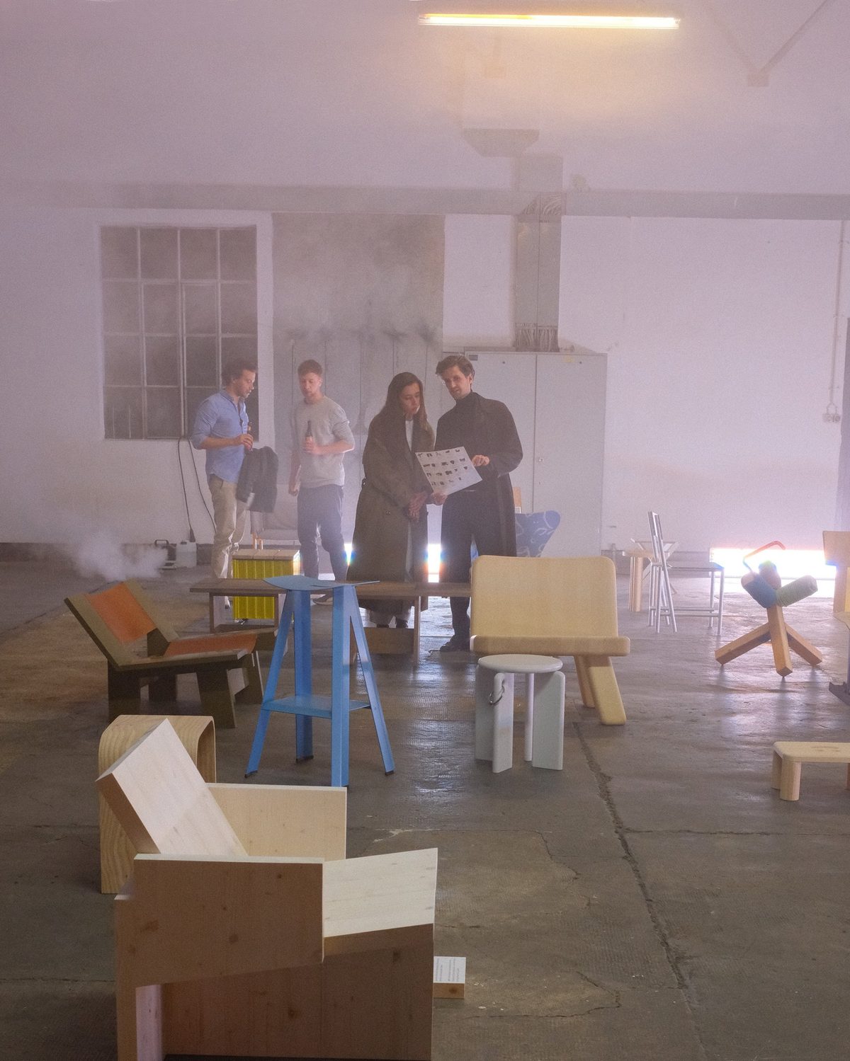 Visitors reading the exhibition sheet in the hazy hall between the chairs